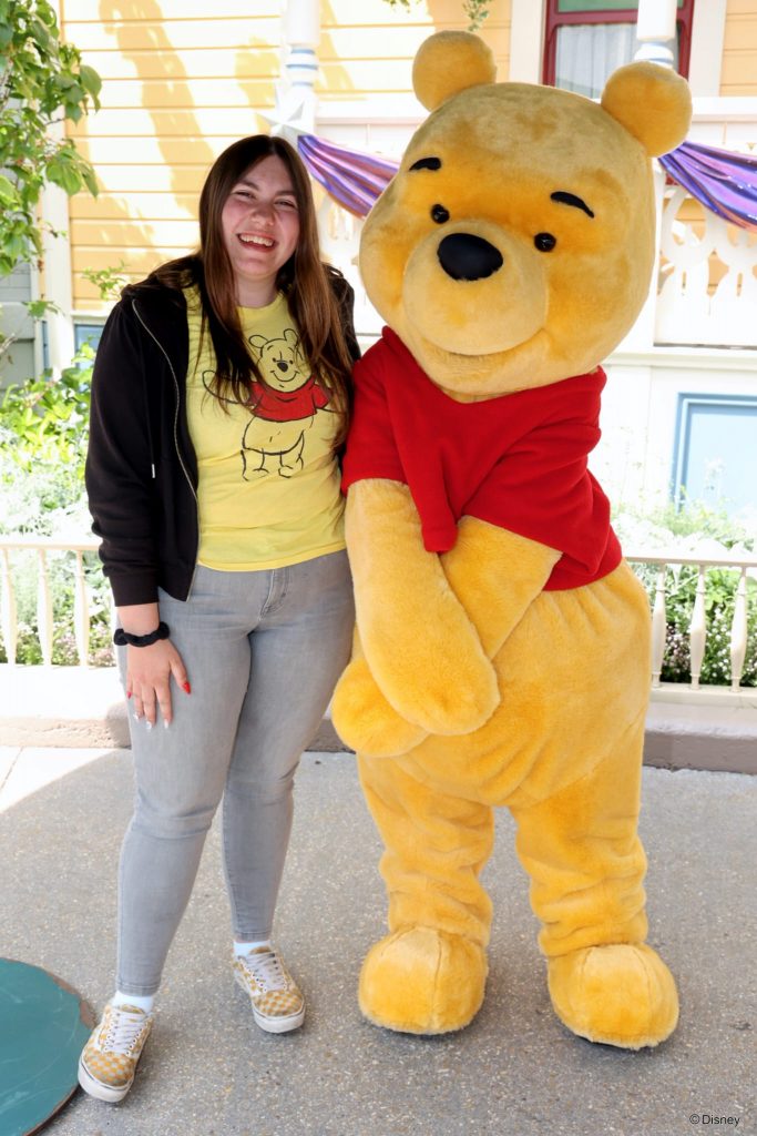 Redaktionsmitglied Layla steht neben dem Charakter Winnie Puuh im Disneyland Paris bei einem Meet & Greet.