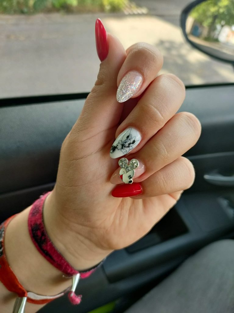 Blick auf die Finger einer Frauenhand. Auf den Fingernägeln ist ein Disney-Design als Nagellack angebracht. Auf dem Mittelfinger ist eine Minnie Mouse zu sehen und auf dem Ringfinger ist der Kopf von Mickey Mouse.